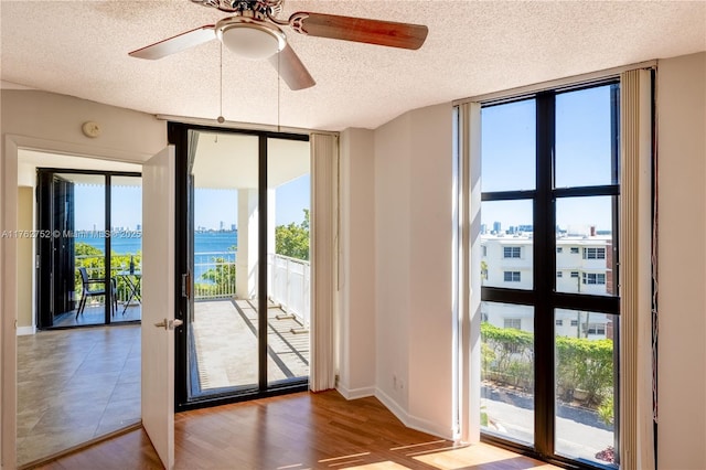 doorway featuring a textured ceiling, a wall of windows, ceiling fan, and wood finished floors