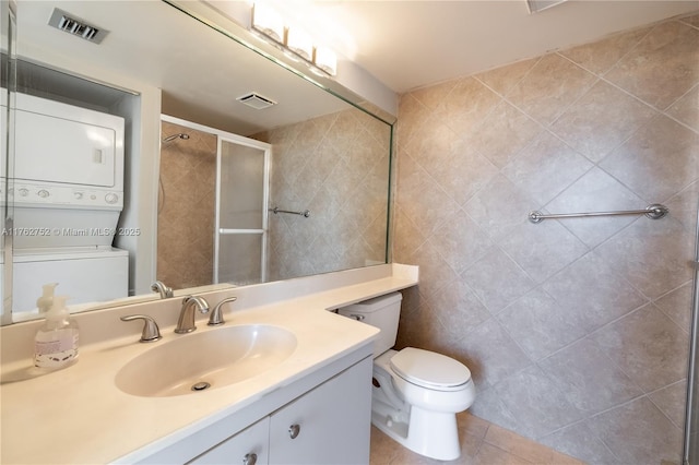 full bath with tile patterned floors, visible vents, stacked washer and clothes dryer, a stall shower, and vanity