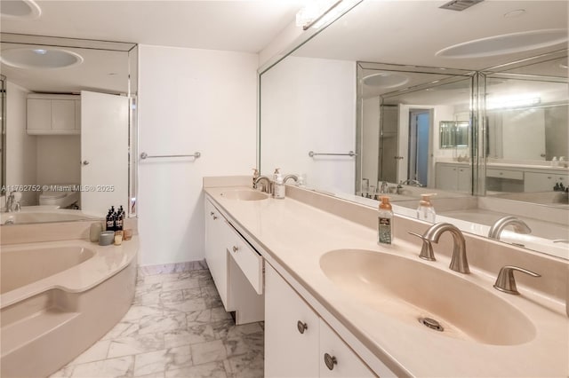 bathroom featuring double vanity, marble finish floor, a garden tub, and a sink