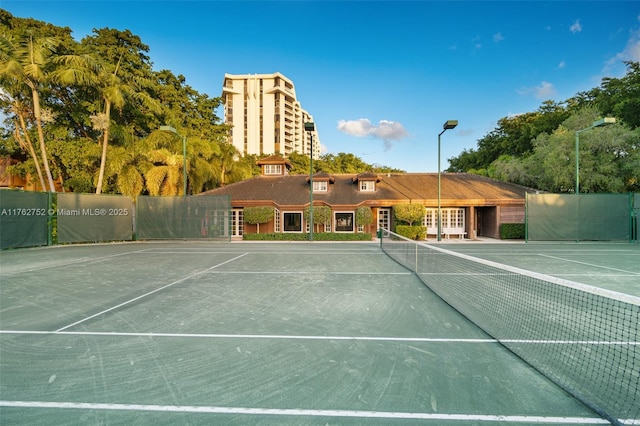 view of tennis court with community basketball court and fence