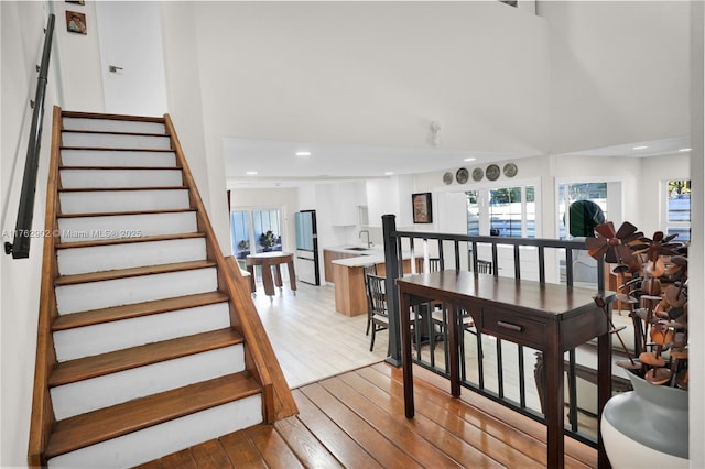 interior space with recessed lighting, wood-type flooring, a high ceiling, and a healthy amount of sunlight