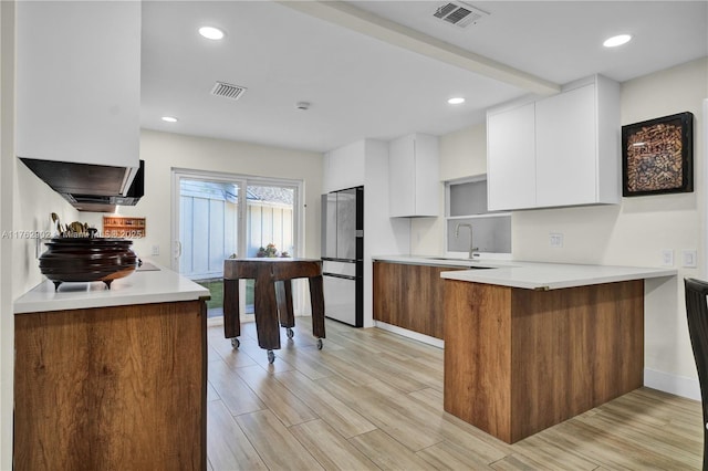 kitchen with a sink, visible vents, white cabinets, and freestanding refrigerator