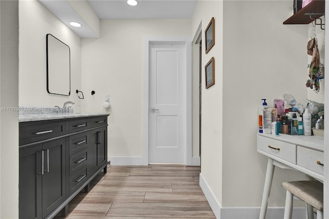 bathroom with recessed lighting, baseboards, wood finished floors, and vanity