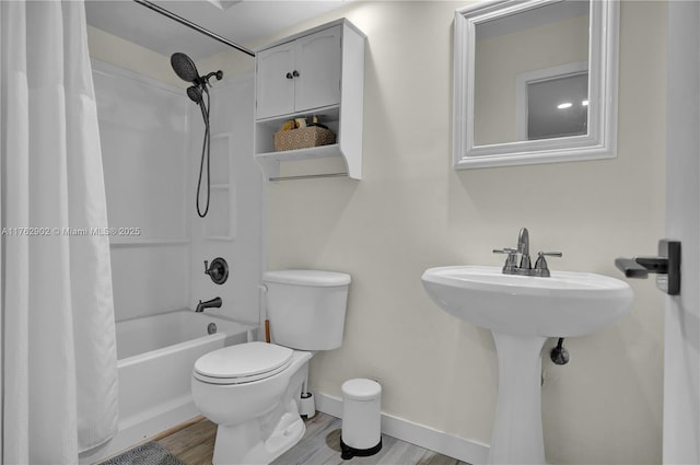 bathroom featuring baseboards, toilet, wood finished floors, and shower / bath combo