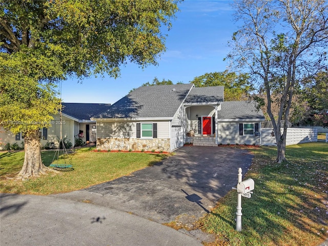 ranch-style house with aphalt driveway, stone siding, roof with shingles, and a front yard