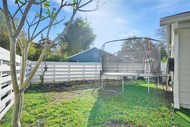 view of yard with a trampoline and a fenced backyard