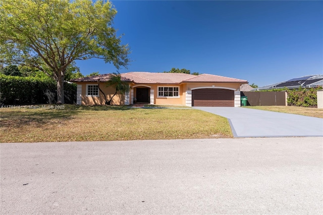 ranch-style home featuring fence, a front lawn, concrete driveway, a garage, and a tile roof