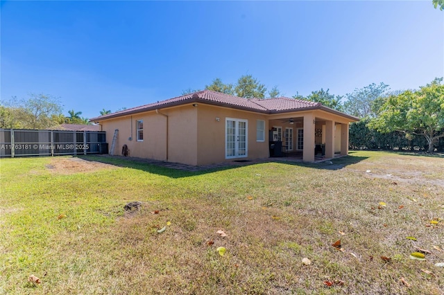 back of property featuring stucco siding, a lawn, french doors, ceiling fan, and a tiled roof