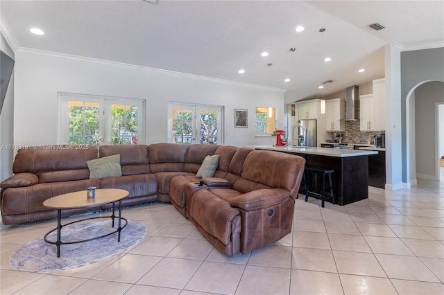 living room featuring crown molding, light tile patterned floors, arched walkways, and visible vents