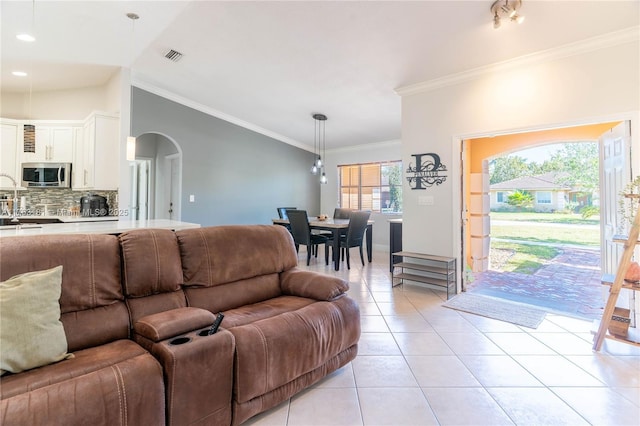 living room featuring visible vents, ornamental molding, arched walkways, light tile patterned floors, and lofted ceiling