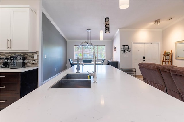 kitchen featuring ornamental molding, a sink, white cabinetry, tasteful backsplash, and open floor plan