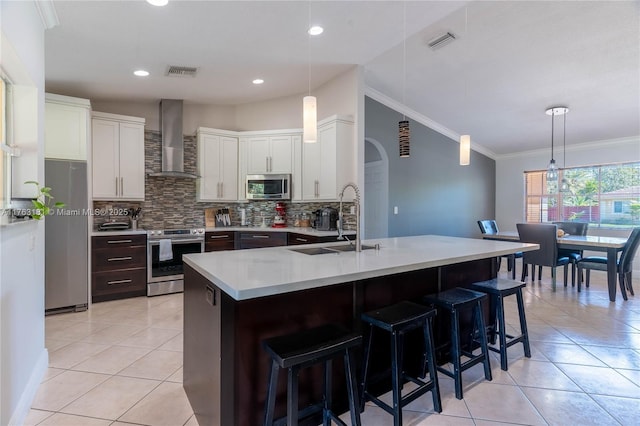 kitchen with a sink, stainless steel appliances, visible vents, and wall chimney exhaust hood