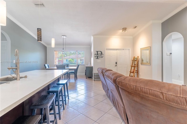 living area featuring arched walkways, light tile patterned floors, and ornamental molding