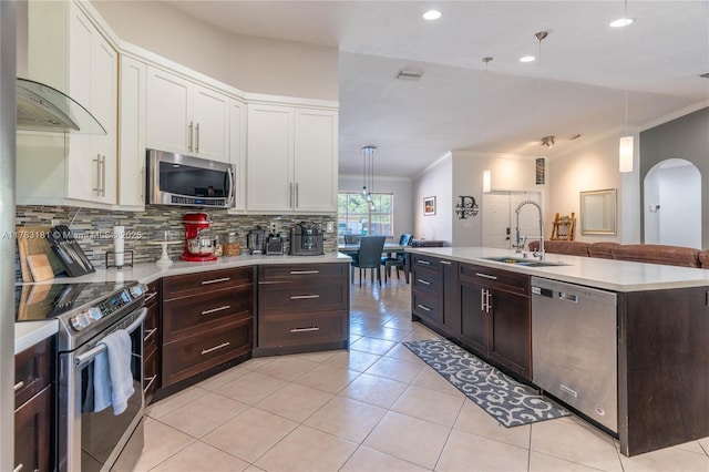 kitchen with light countertops, stainless steel appliances, white cabinetry, wall chimney exhaust hood, and a sink