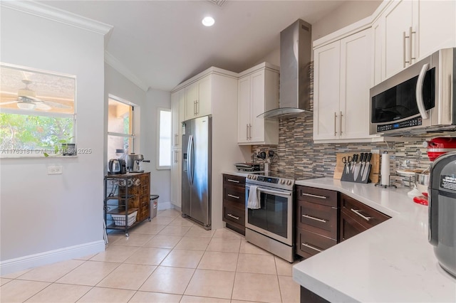 kitchen with wall chimney range hood, tasteful backsplash, stainless steel appliances, light countertops, and light tile patterned floors