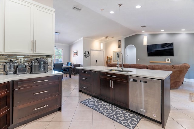 kitchen featuring light tile patterned flooring, arched walkways, a sink, light countertops, and dishwasher