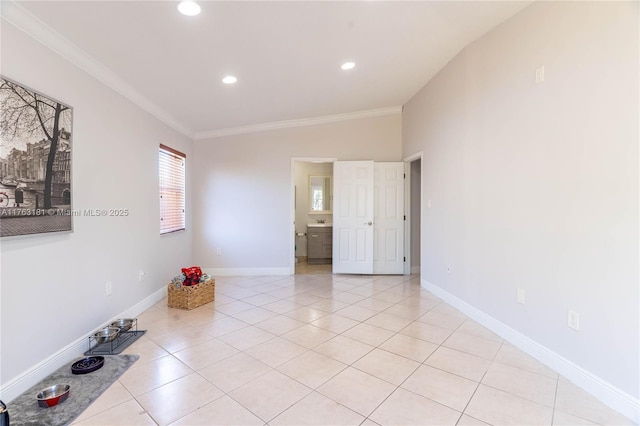 spare room with crown molding, light tile patterned floors, and baseboards