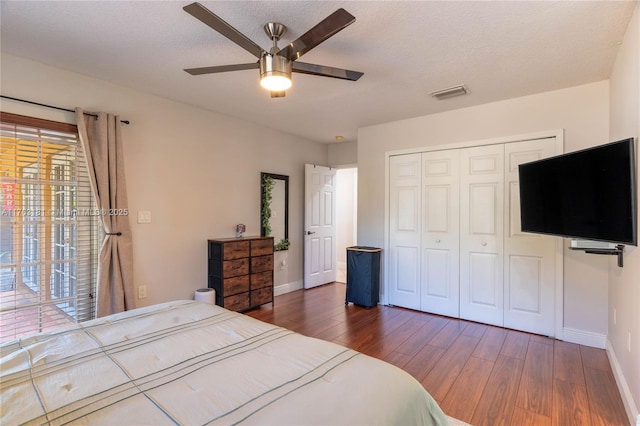 bedroom with visible vents, wood finished floors, a closet, baseboards, and ceiling fan