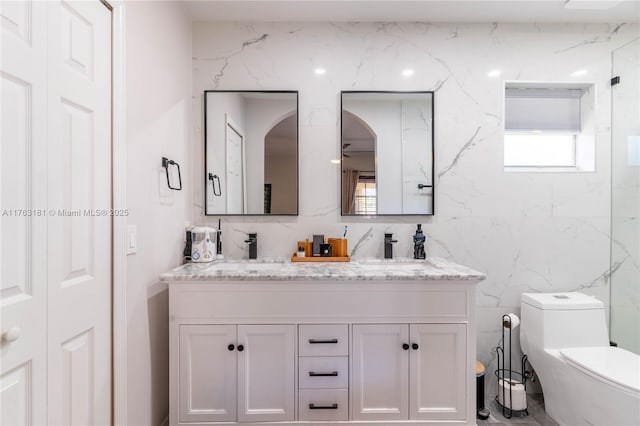 bathroom with a sink, toilet, and double vanity