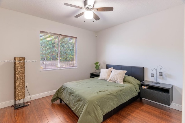 bedroom with ceiling fan, baseboards, and wood finished floors