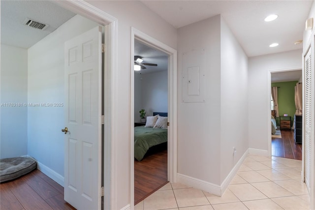 corridor with light tile patterned floors, visible vents, and baseboards