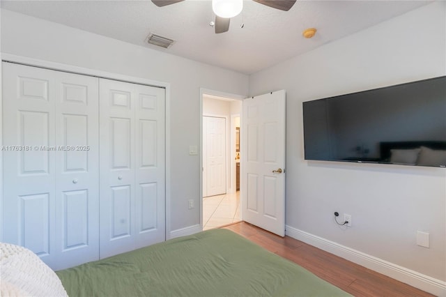 bedroom with visible vents, ceiling fan, baseboards, wood finished floors, and a closet