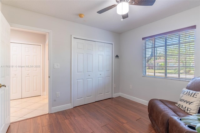 living area featuring baseboards, light wood-style floors, and ceiling fan