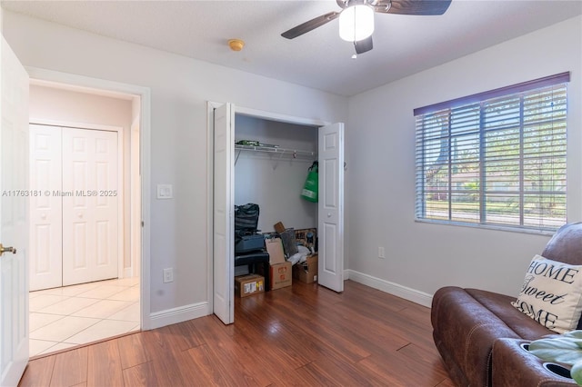 living area with wood finished floors, baseboards, and ceiling fan