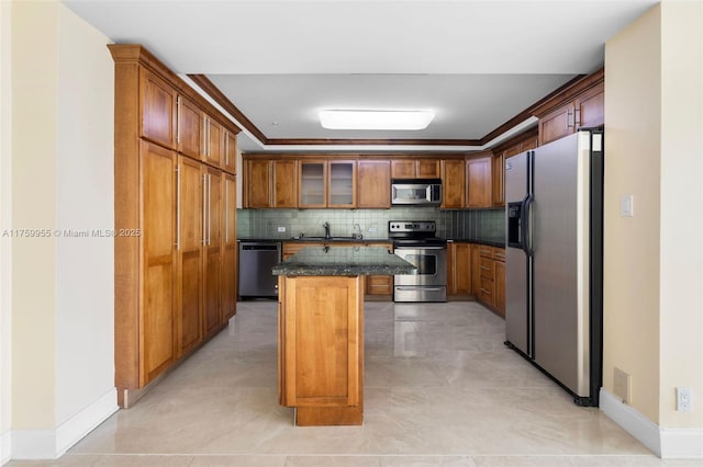 kitchen featuring a sink, tasteful backsplash, a kitchen island, appliances with stainless steel finishes, and brown cabinetry