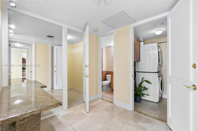 bathroom featuring visible vents, toilet, and stacked washer / drying machine