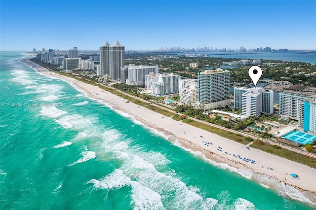 drone / aerial view featuring a view of city, a water view, and a beach view