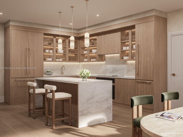 bar with tasteful backsplash, black electric stovetop, pendant lighting, light wood-style floors, and a sink