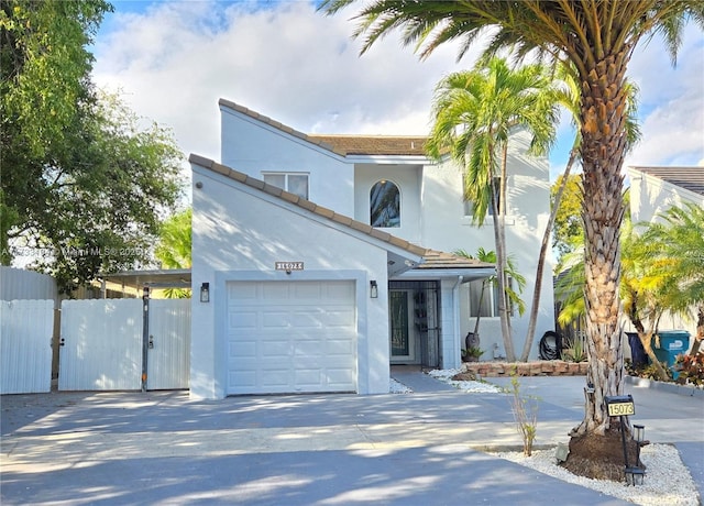 view of front of house featuring fence, concrete driveway, stucco siding, a garage, and a gate