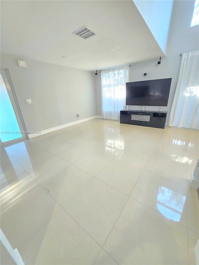 unfurnished living room with tile patterned flooring, visible vents, and baseboards