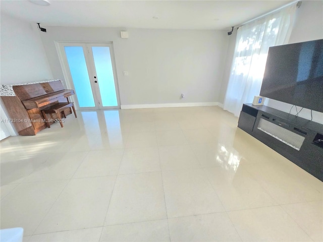 unfurnished living room with tile patterned flooring, french doors, and baseboards