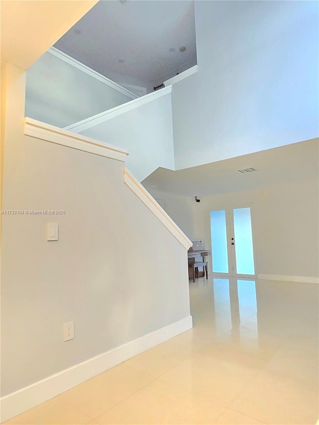 staircase with a high ceiling, baseboards, and visible vents