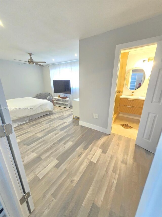 bedroom with connected bathroom, baseboards, and wood finished floors