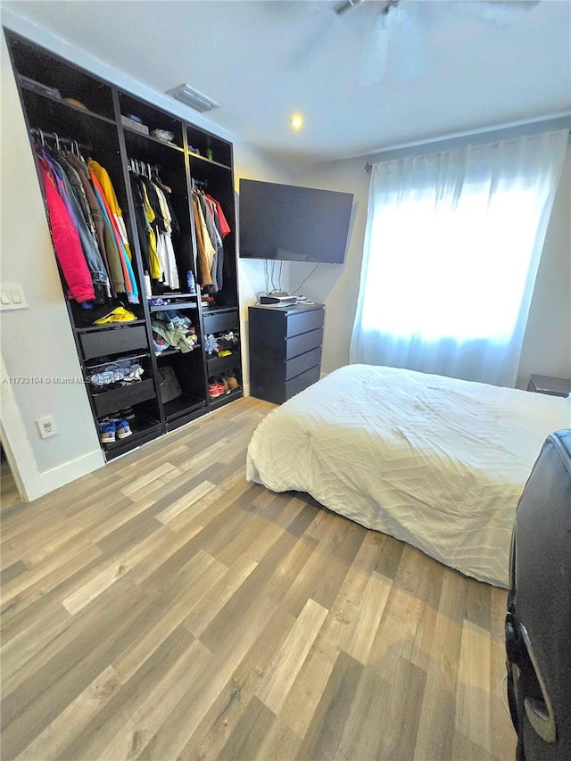 bedroom with a closet, visible vents, baseboards, and wood finished floors