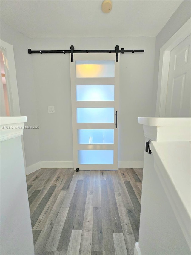 entrance foyer with a barn door, baseboards, and wood finished floors