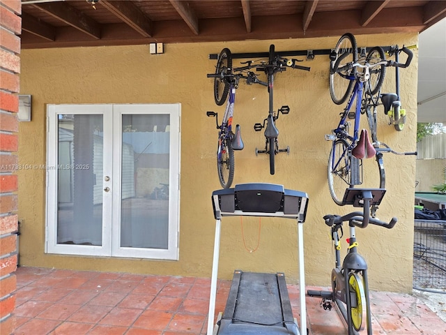 workout area with tile patterned floors, french doors, and a textured wall