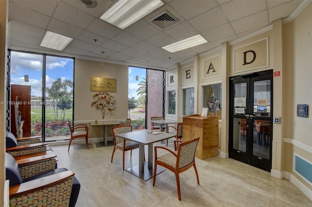 dining space featuring a drop ceiling, visible vents, baseboards, and floor to ceiling windows