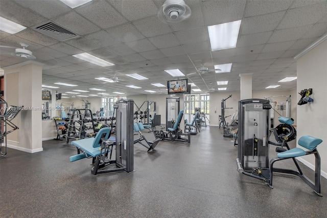 exercise room with a paneled ceiling, visible vents, and baseboards