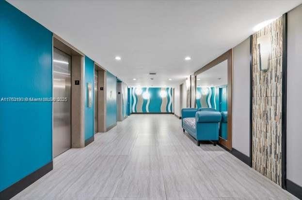 hall with elevator, recessed lighting, and light wood-type flooring