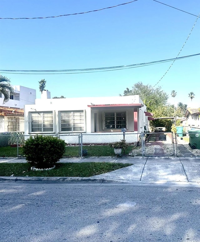 view of front of home with a fenced front yard, driveway, a carport, and a gate