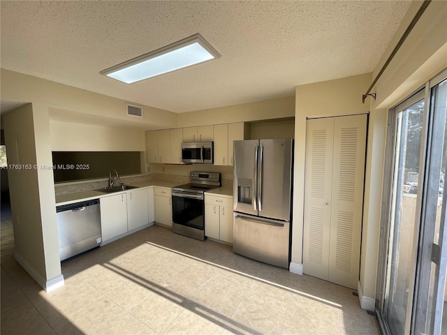 kitchen featuring visible vents, a sink, a textured ceiling, stainless steel appliances, and light countertops