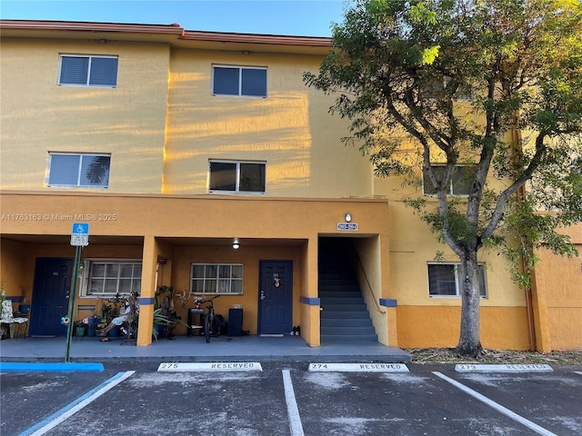 view of property featuring stairway and uncovered parking