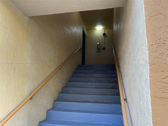 stairway featuring a textured wall