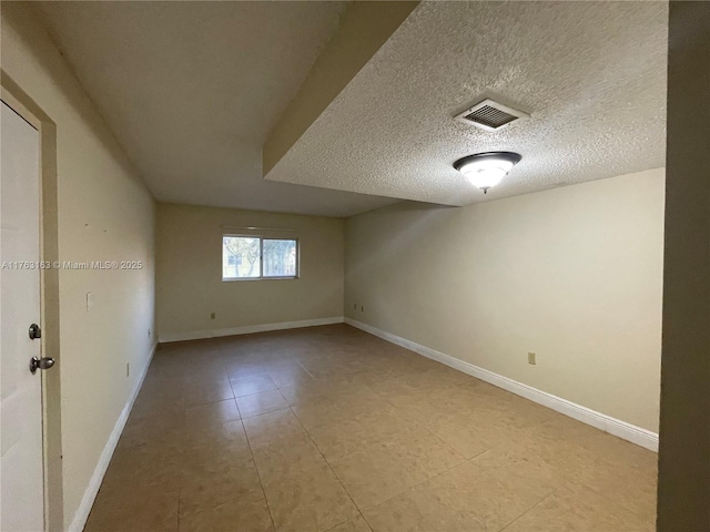 unfurnished room featuring light tile patterned floors, visible vents, a textured ceiling, and baseboards