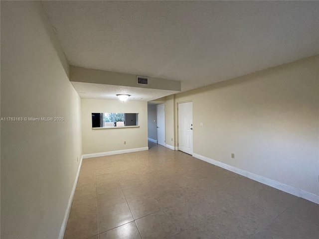 unfurnished room with visible vents, baseboards, and a textured ceiling