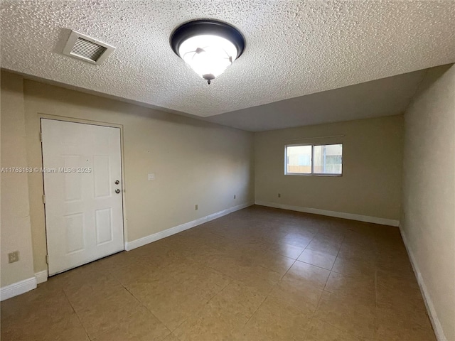 empty room featuring visible vents, baseboards, and a textured ceiling